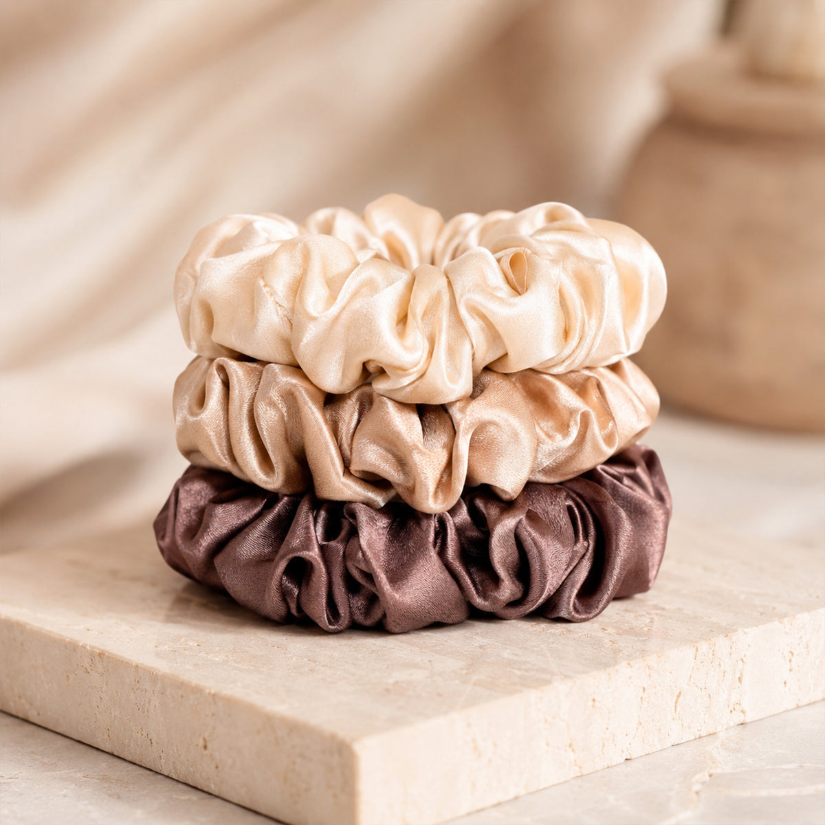 Set of three large Silk Scrunchies in cream, champagne and brown, stacked on a stone tray